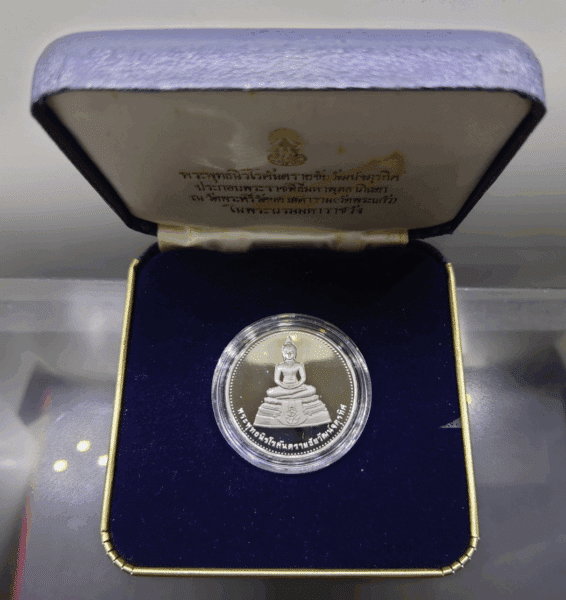 The Phra Phuttha Nirokantarai amulet, consecrated by the Chaipattana Foundation in a grand Buddhist blessing ceremony at Wat Phra Sri Rattana, is made of polished silver with a sandblasted finish. It is a large size amulet, minted in 1996 (B.E. 2539), and comes with its original box.